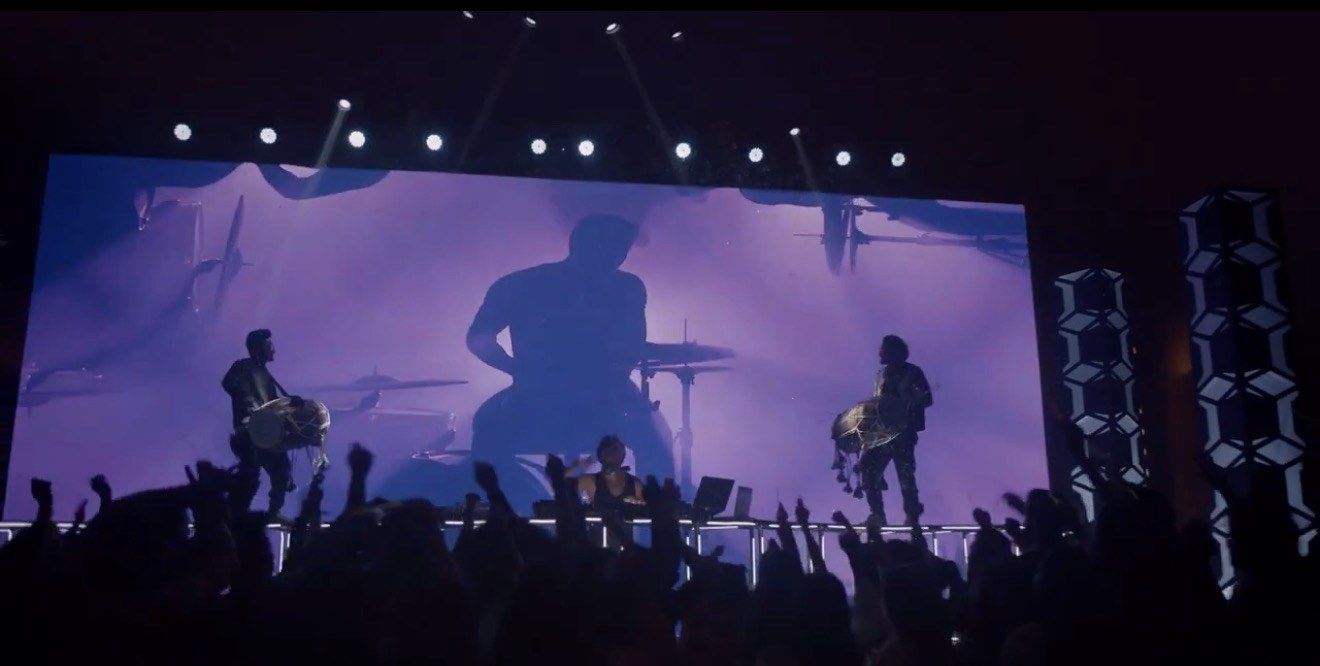 Drummers on stage in front of a large LED screen